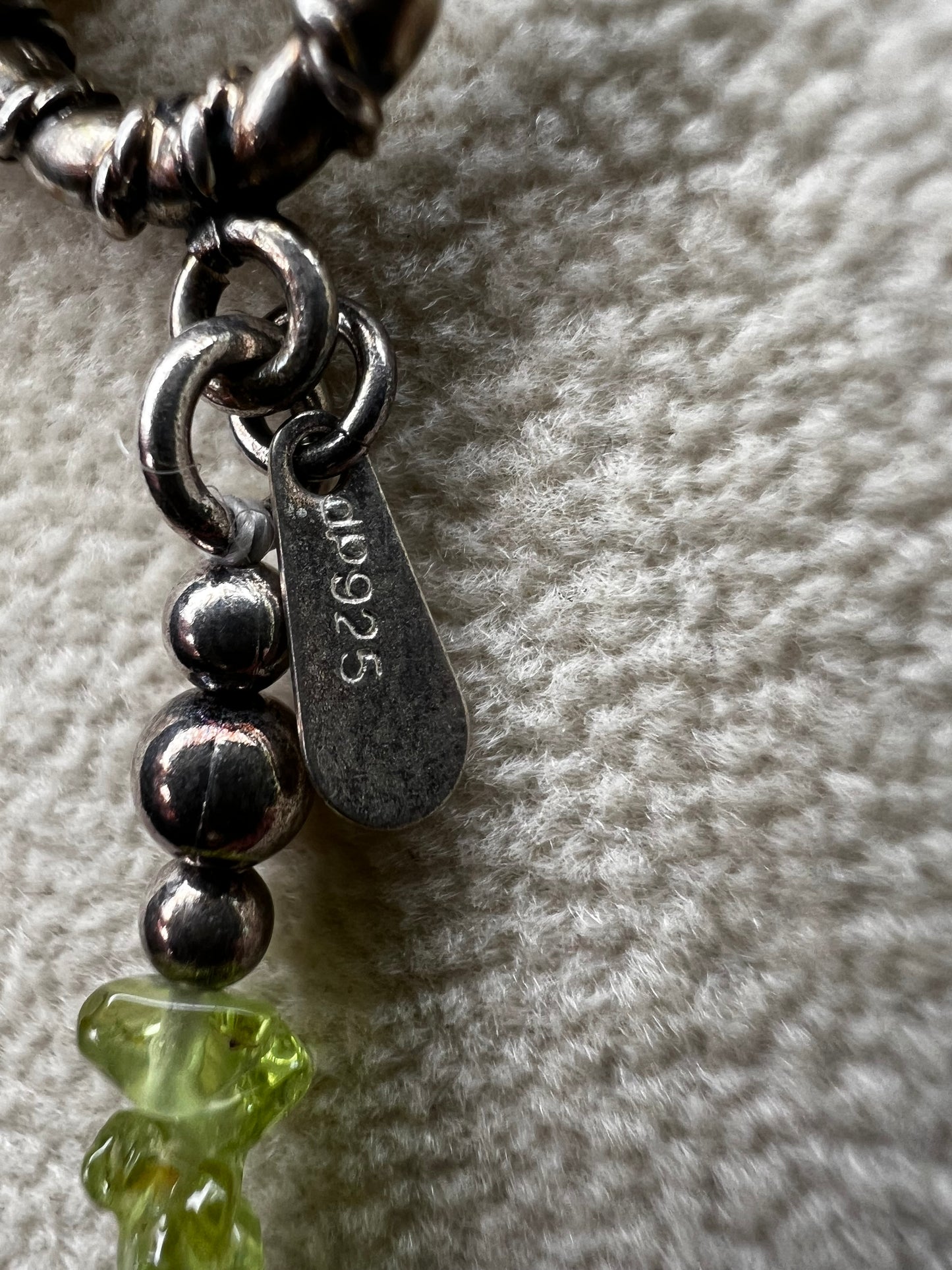 This 36-inch necklace features natural peridot chips expertly strung and paired with sterling silver components. Its vibrant green hues bring a refreshing touch, while sterling silver ensures durability and elegance. Made in India.
