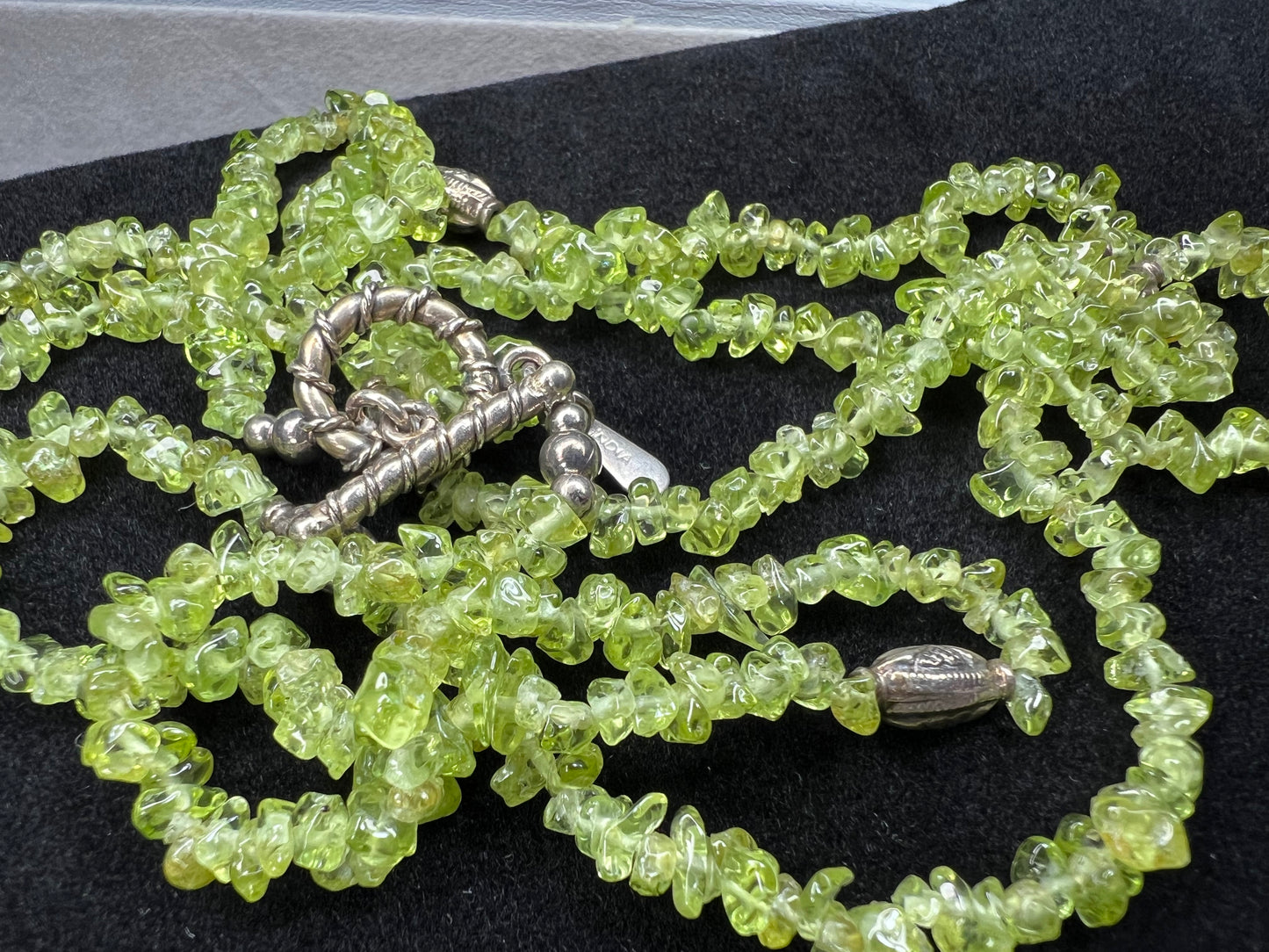 This 36-inch necklace features natural peridot chips expertly strung and paired with sterling silver components. Its vibrant green hues bring a refreshing touch, while sterling silver ensures durability and elegance. Made in India.