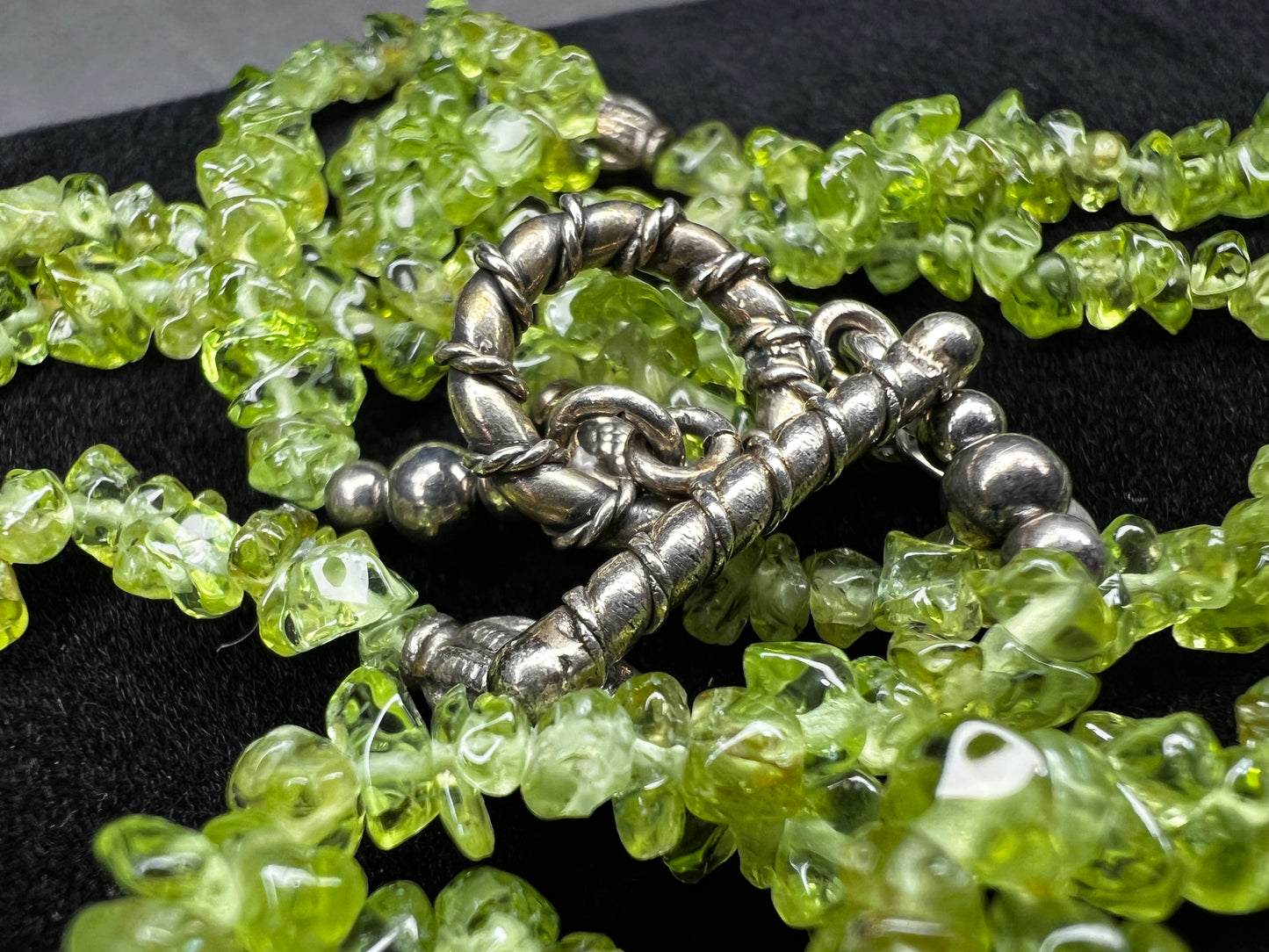 This 36-inch necklace features natural peridot chips expertly strung and paired with sterling silver components. Its vibrant green hues bring a refreshing touch, while sterling silver ensures durability and elegance. Made in India.