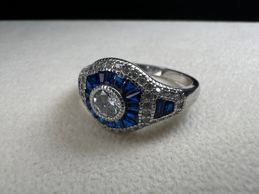 This sterling silver ring showcases exquisite Art Deco design. Featuring captivating blue spinel and quartz stones, it highlights meticulous craftsmanship and a balanced color palette, making it a standout piece for collectors and connoisseurs of fine jewelry. Signed MM.