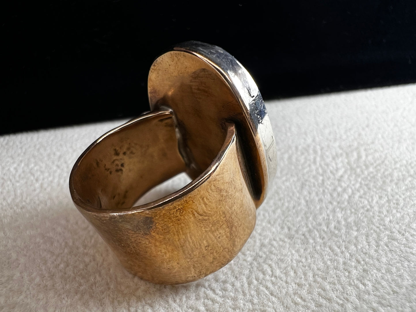 This ring by Loving Anvil features a dendritic limestone cabochon, which displays striking fern-like black inclusions that resemble a natural landscape. The stone is set in sterling silver against a brass band with a thin overlay of gold.