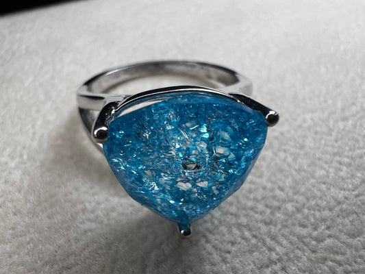 This sterling silver ring showcases a large, blue trilliant cut crackled quartz, creating a captivating centerpiece. Perfect for adding a touch of elegance and distinctiveness to any outfit.
