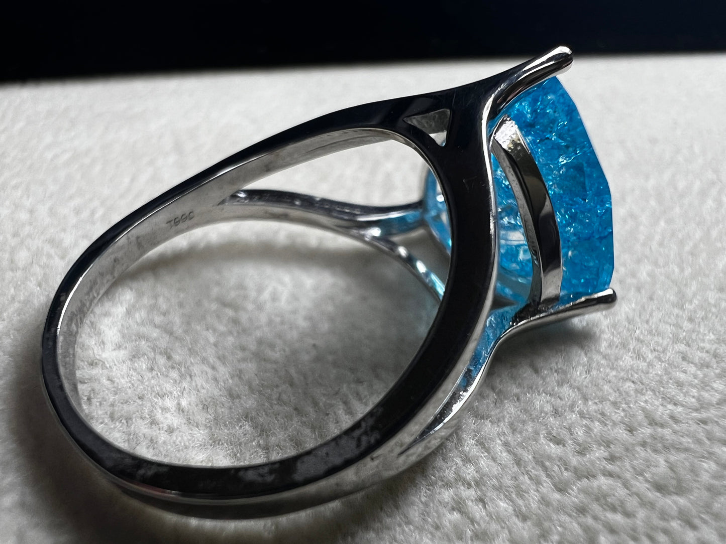 This sterling silver ring showcases a large, blue trilliant cut crackled quartz, creating a captivating centerpiece. Perfect for adding a touch of elegance and distinctiveness to any outfit.