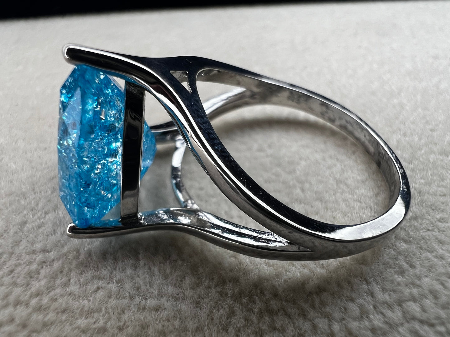 This sterling silver ring showcases a large, blue trilliant cut crackled quartz, creating a captivating centerpiece. Perfect for adding a touch of elegance and distinctiveness to any outfit.