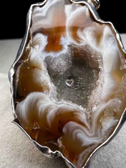 This exquisite ring by Loving Anvil showcases a natural druzy agate slice wrapped in fine sterling silver. Delicately embellished with two small gold accents, the design highlights the stone’s unique open space, creating a one-of-a-kind piece.