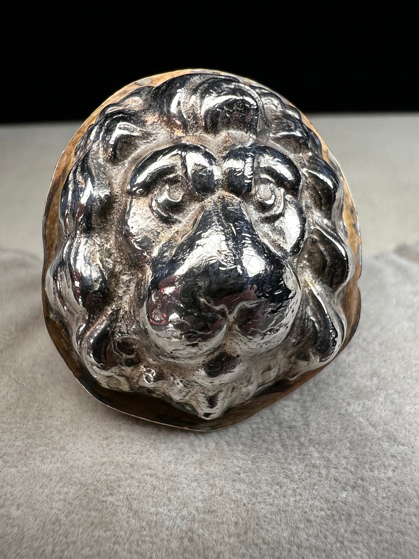 This sterling silver ring by Loving Anvil features a striking lion's head design, expertly crafted for a bold and unique statement. The backing plate is finished in fine gold, adding a stylish two-tone effect.