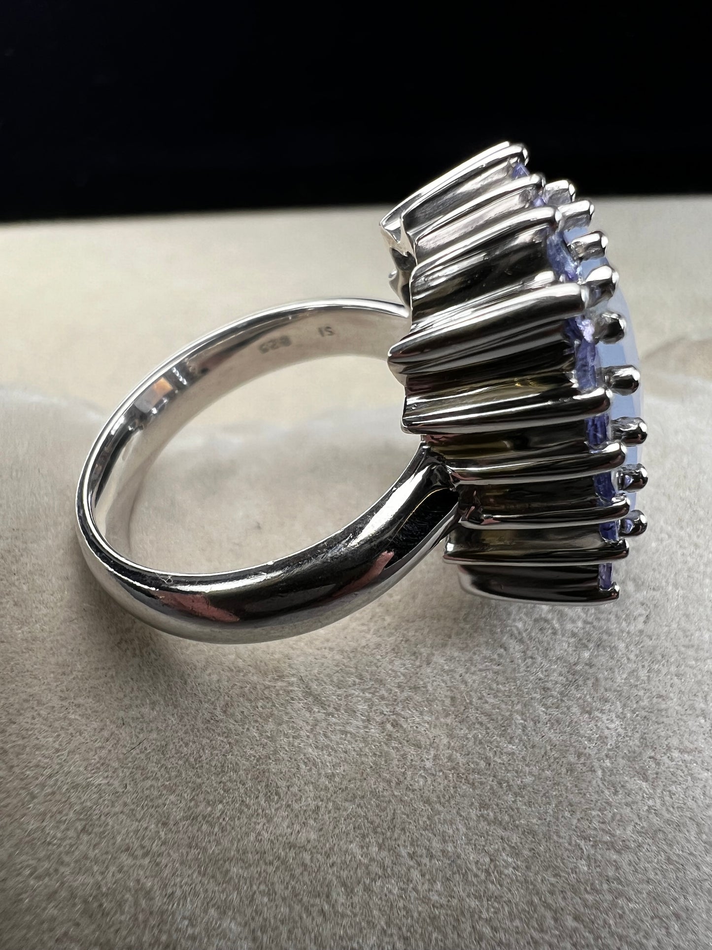 This sterling silver ring combines comfortable wear with captivating style. Featuring a large chalcedony centerpiece surrounded by sparkling tanzanite accent stones, this piece offers a stunning and elegant look.