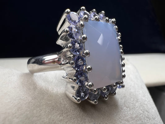 This sterling silver ring combines comfortable wear with captivating style. Featuring a large chalcedony centerpiece surrounded by sparkling tanzanite accent stones, this piece offers a stunning and elegant look.
