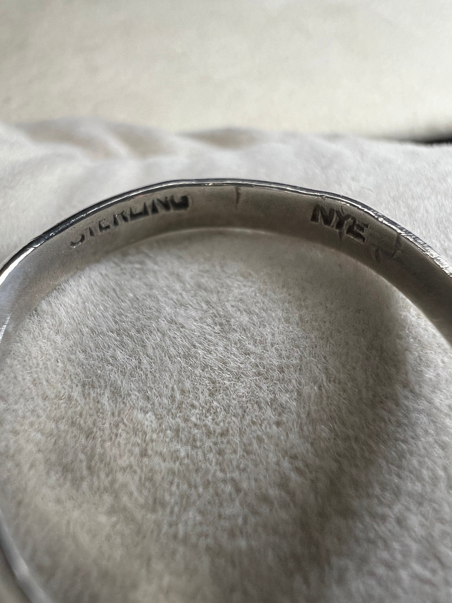 This sterling silver ring by Stuart Nye showcases a delicate dogwood flower design, combining artistry with elegant craftsmanship. Its refined detail makes it a meaningful accessory that adds a touch of nature-inspired beauty to any outfit.