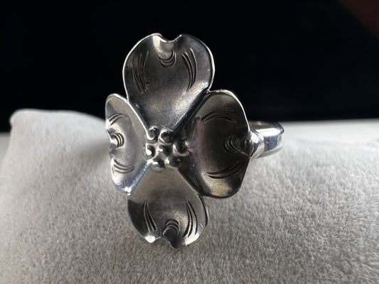 This sterling silver ring by Stuart Nye showcases a delicate dogwood flower design, combining artistry with elegant craftsmanship. Its refined detail makes it a meaningful accessory that adds a touch of nature-inspired beauty to any outfit.