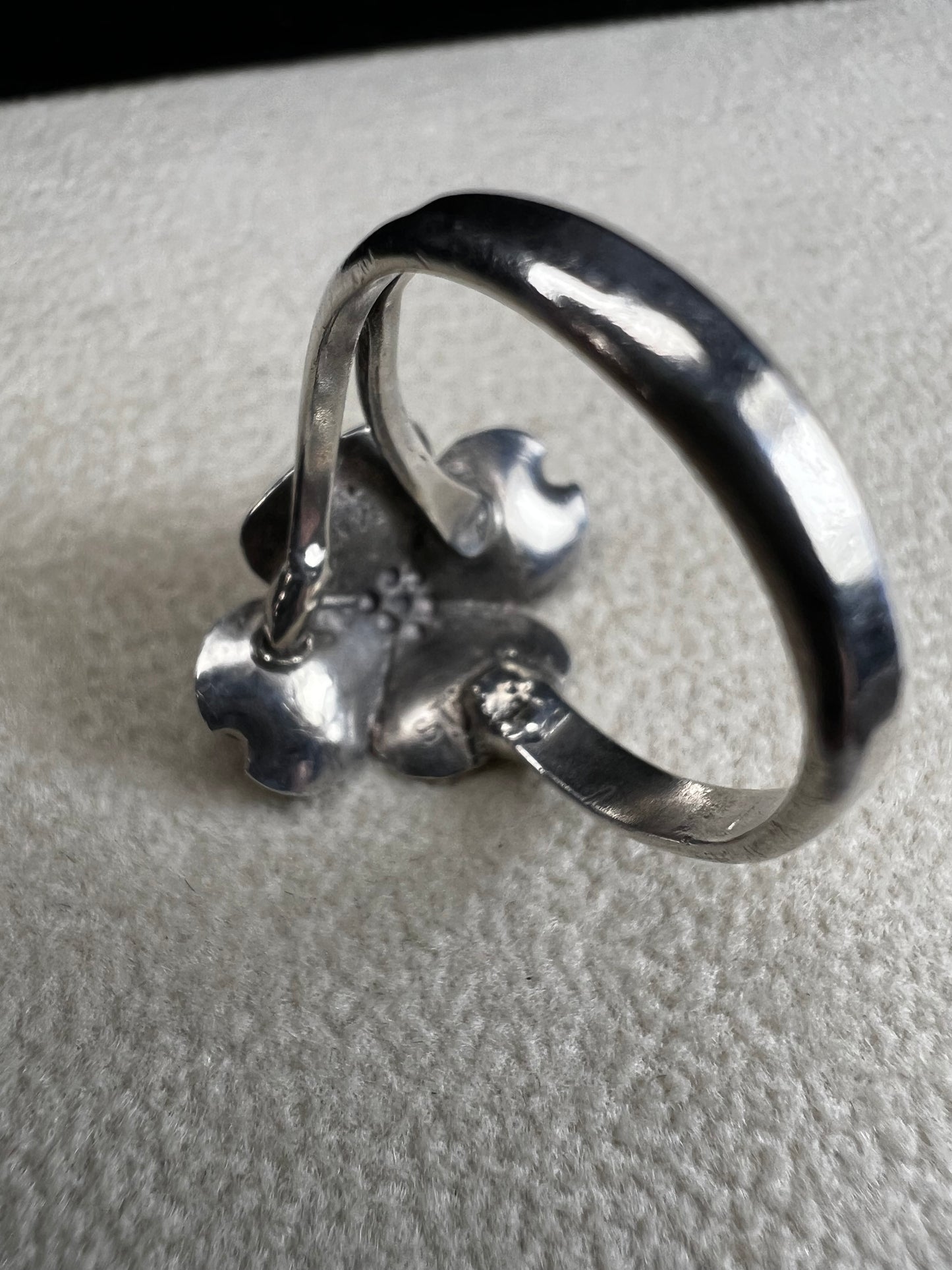 This sterling silver ring by Stuart Nye showcases a delicate dogwood flower design, combining artistry with elegant craftsmanship. Its refined detail makes it a meaningful accessory that adds a touch of nature-inspired beauty to any outfit.