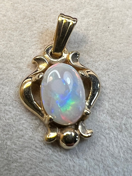 Set amid 14 karat gold, this beautiful opal pendant flashes hues of red, green, blue and yellow. Pair it with one of our gold chains.