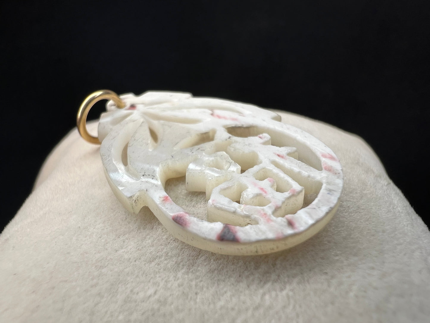 This beautiful pendant is hand-carved from mother of pearl. It is fitted with a 14 karat gold jump ring/bail.