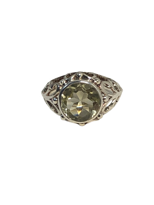 This sterling silver ring features a pale green spinel in a round cut. It is set amid beautiful silver detailing.