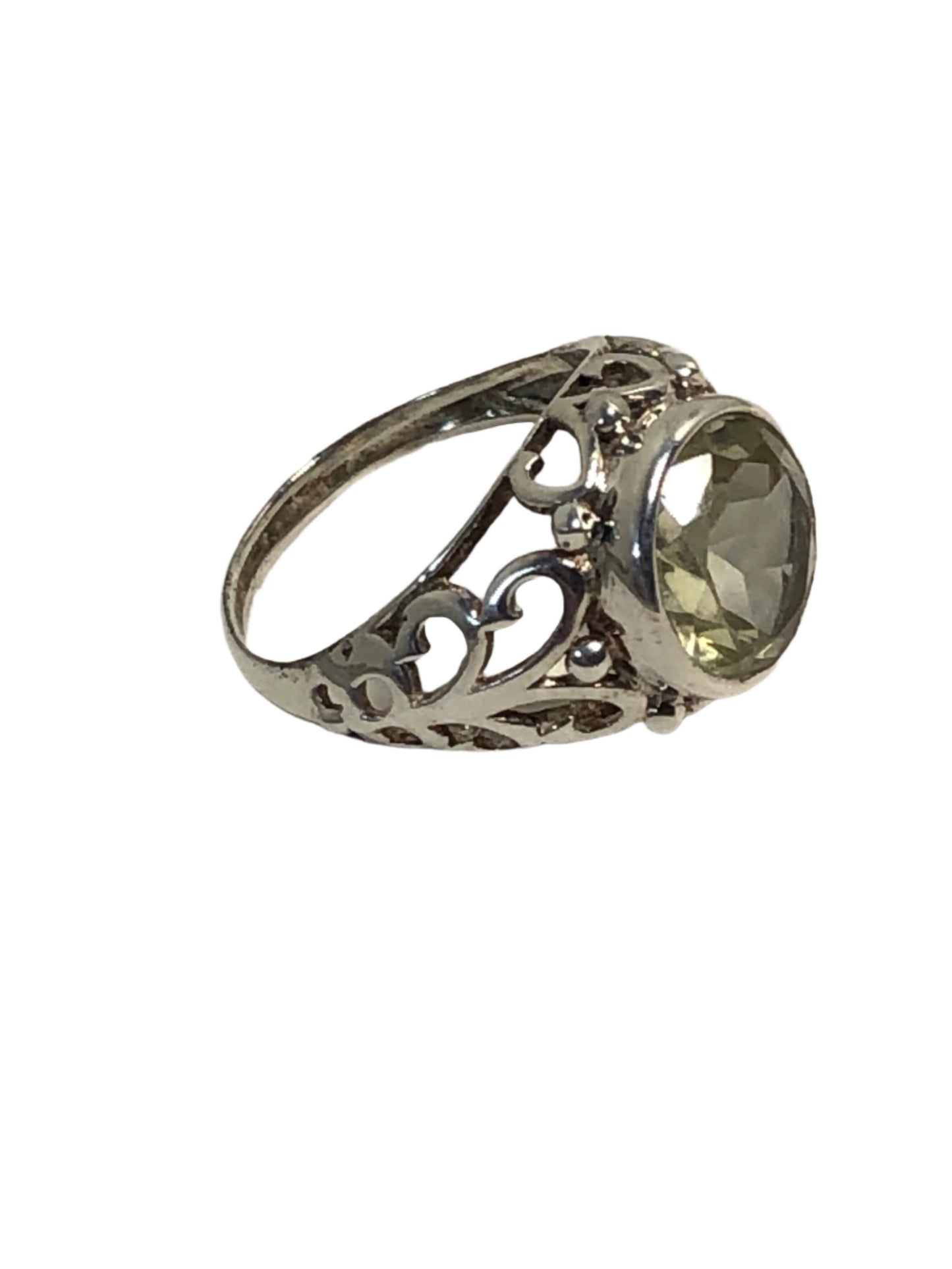 This sterling silver ring features a pale green spinel in a round cut. It is set amid beautiful silver detailing.
