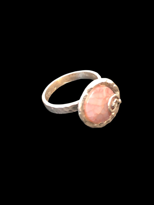 This unique hand-hammered sterling silver ring showcases a stunning pinkish natural stone. Boasting intricate and stylish detailing, this intriguing piece is perfect for any outfit. Made in Israel.
