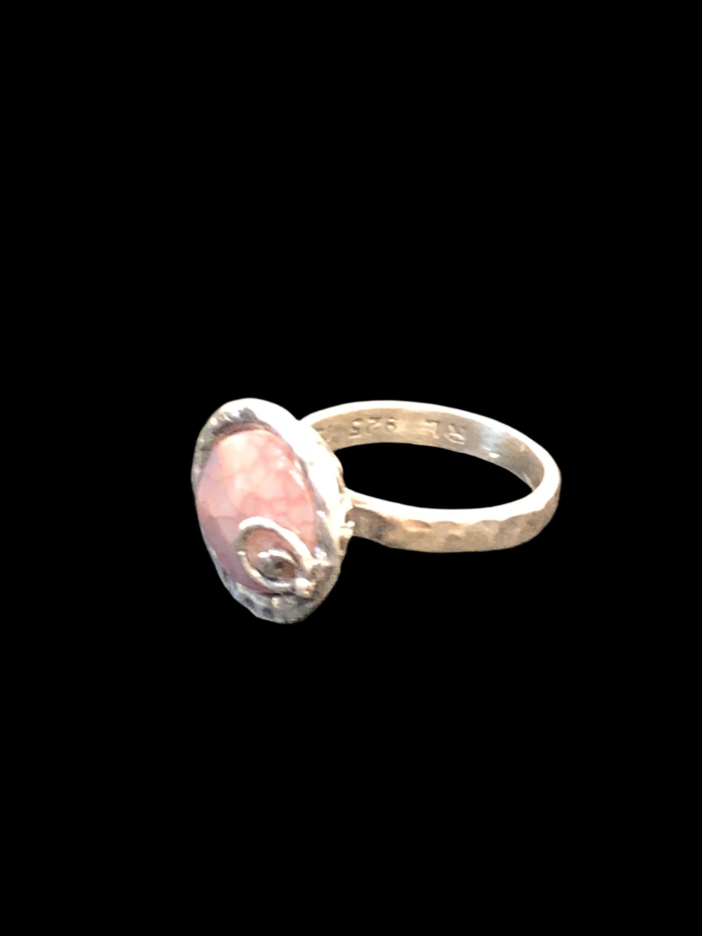 This unique hand-hammered sterling silver ring showcases a stunning pinkish natural stone. Boasting intricate and stylish detailing, this intriguing piece is perfect for any outfit. Made in Israel.