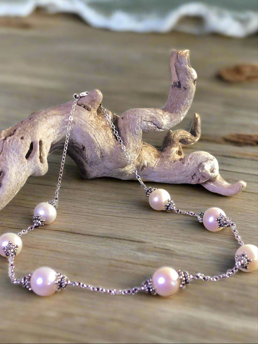 Indulge in timeless elegance with this necklace. Each pearl is flanked with decorative sterling silver accents and spaced on a cable-link sterling silver chain.