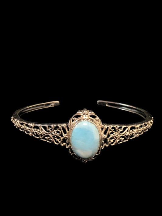 This sterling silver cuff bracelet boasts a beautiful oval chalcedony stone. It is surrounded by a classy filigree setting and band.