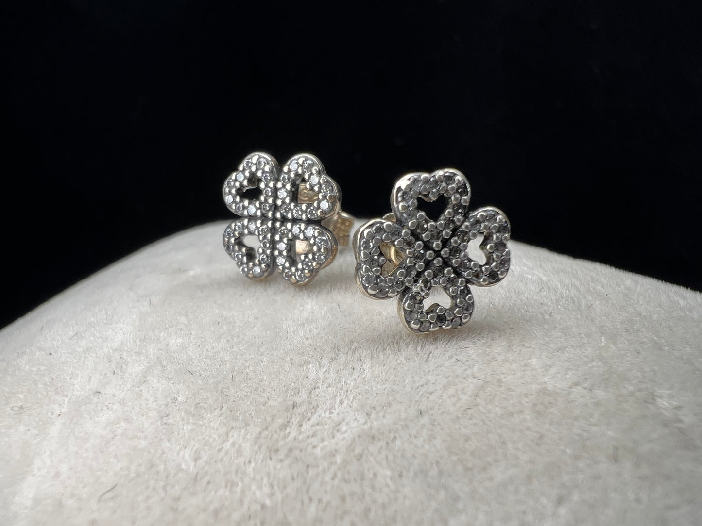 These are beautiful sterling silver earrings. They are shaped as four-leaf clovers with heart designs in each leaf and set with small clear stones throughout.