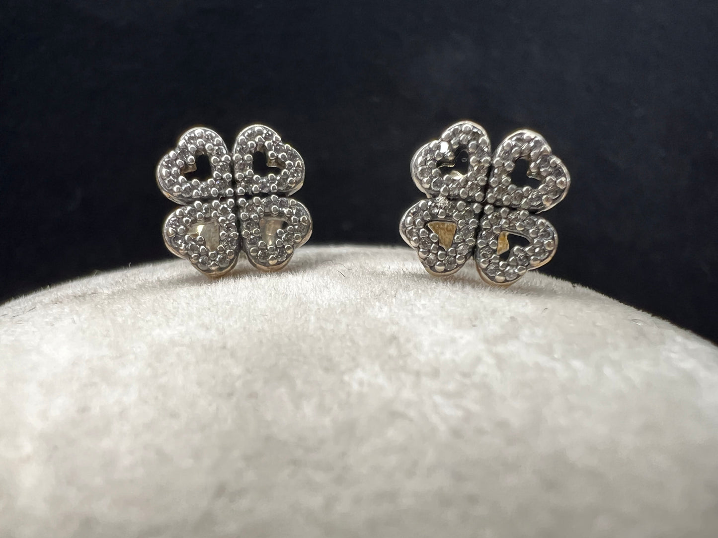 These are beautiful sterling silver earrings. They are shaped as four-leaf clovers with heart designs in each leaf and set with small clear stones throughout.