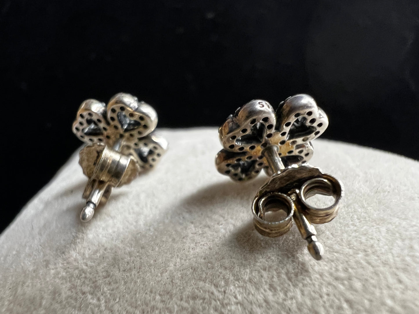 These are beautiful sterling silver earrings. They are shaped as four-leaf clovers with heart designs in each leaf and set with small clear stones throughout.