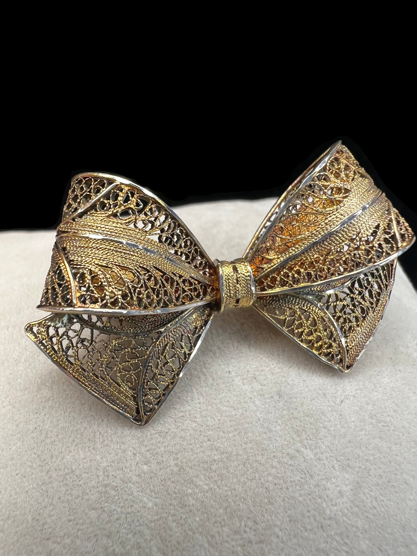 If you like antique jewelry, this filigree bow brooch is a perfect addition for your collection. It is sterling silver with a gold overlay. The nice patina and closure type date it to the late 19th century/early 20th century.
