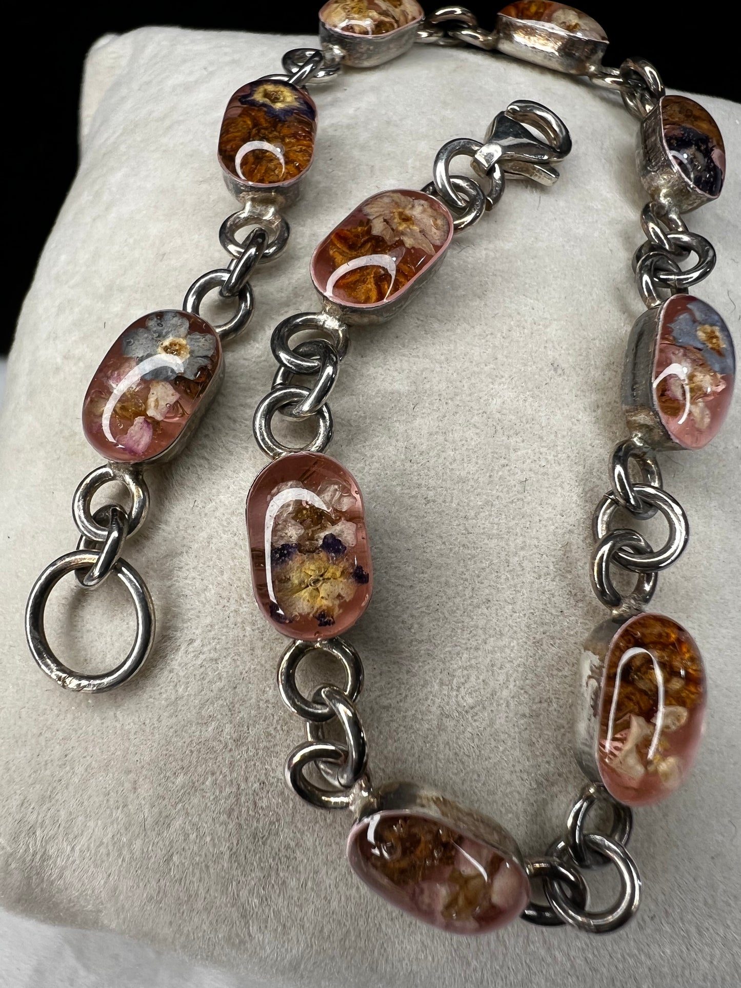 Add a touch of vintage beauty to your outfit with this sterling silver bracelet. Adorned with dried flowers encased in resin cabochons, this unique bracelet will let you bring a piece of nature with you everywhere you go.