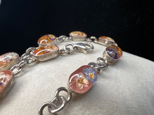 Add a touch of vintage beauty to your outfit with this sterling silver bracelet. Adorned with dried flowers encased in resin cabochons, this unique bracelet will let you bring a piece of nature with you everywhere you go.