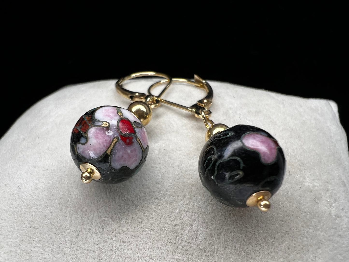 This is a beautiful pair of earrings. They feature cloisonné beads with pink flowers and green leaves set against a black back background to make the flowers pop. Marked 585 (another term for 14 karat gold).