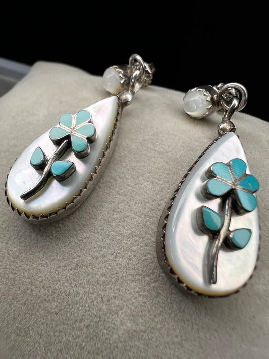 These handmade Zuni sterling silver earrings feature raised turquoise flowers set over luminous mother of pearl. Signed CL Zuni, these teardrop earrings showcase traditional Native American artistry with beautiful depth and dimension.