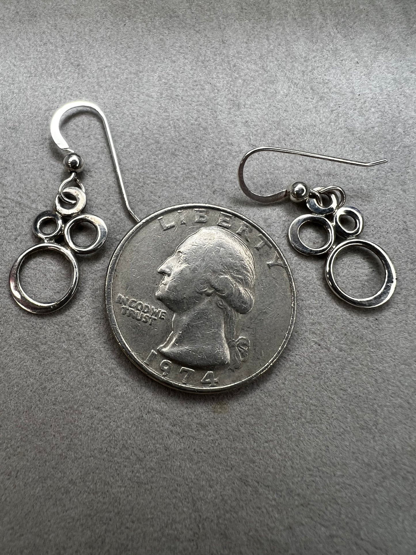 These elegant sterling silver dangle earrings feature an eye-catching arrangement of circles in varying sizes, creating a playful yet minimalist look.