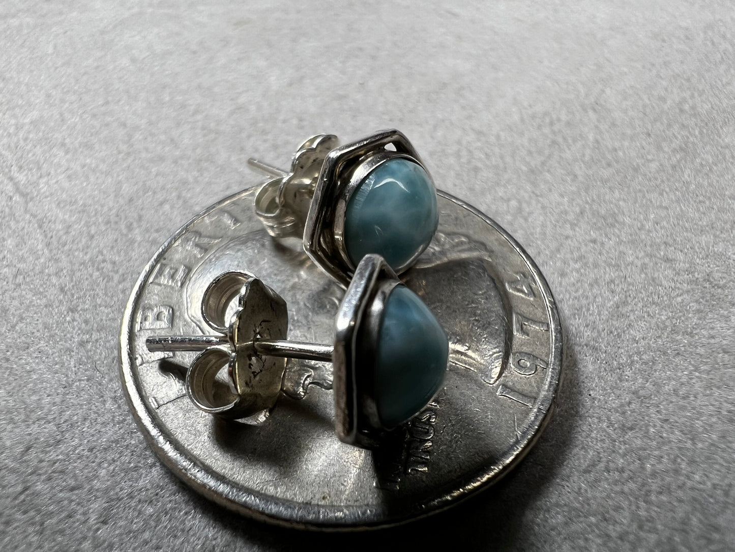 These sterling silver earrings feature natural larimar cabochons from the Dominican Republic set in a hexagon bezel, perfect for a touch of Caribbean charm.
