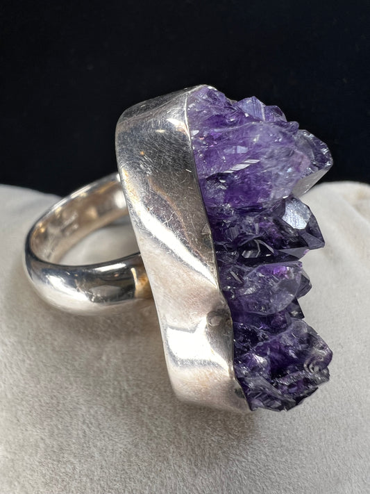 This is a large amethyst specimen ring, made with sterling silver, from designer Charles Albert. Please note that the specimen does have fractures but is priced accordingly -- and this piece deserves to continue on its journey with someone new.