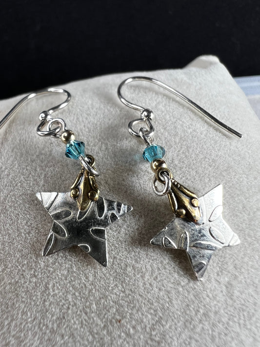These sterling silver earrings are accented with 14-karat gold, creating a two-toned design as the stars dance in the light.