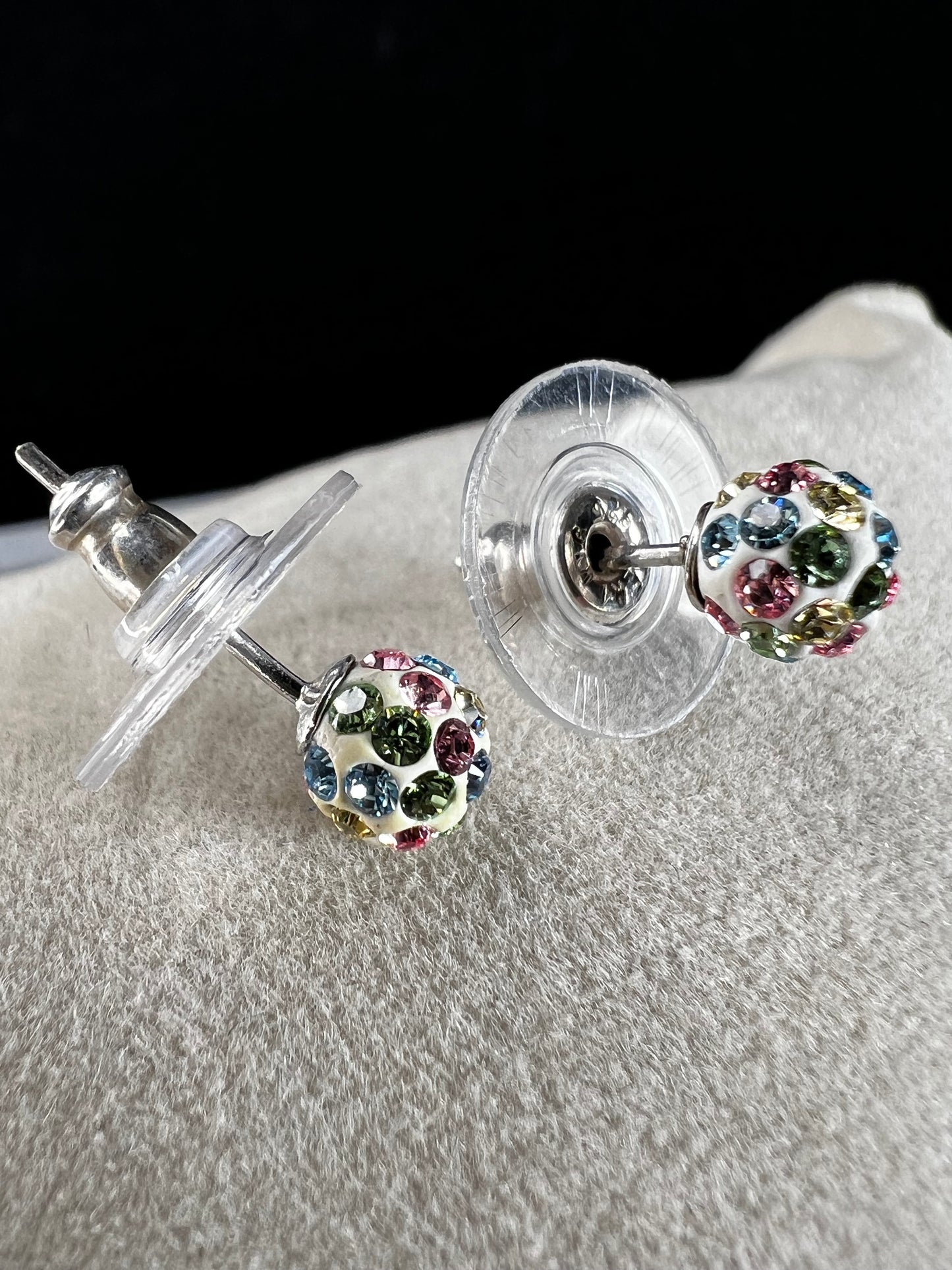 Crafted from sterling silver, these stud earrings are detailed with white enamel and sprinkled with crystals in a variety of colors that create a vibrant sparkle.