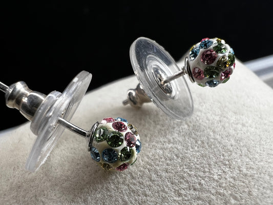 Crafted from sterling silver, these stud earrings are detailed with white enamel and sprinkled with crystals in a variety of colors that create a vibrant sparkle.