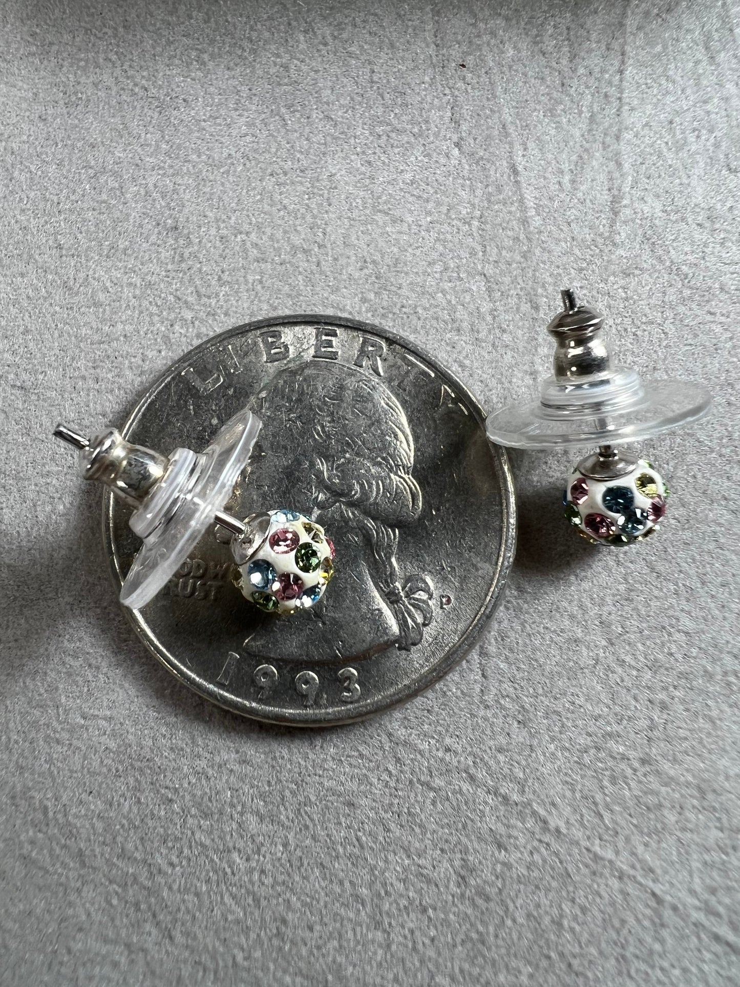 Crafted from sterling silver, these stud earrings are detailed with white enamel and sprinkled with crystals in a variety of colors that create a vibrant sparkle.