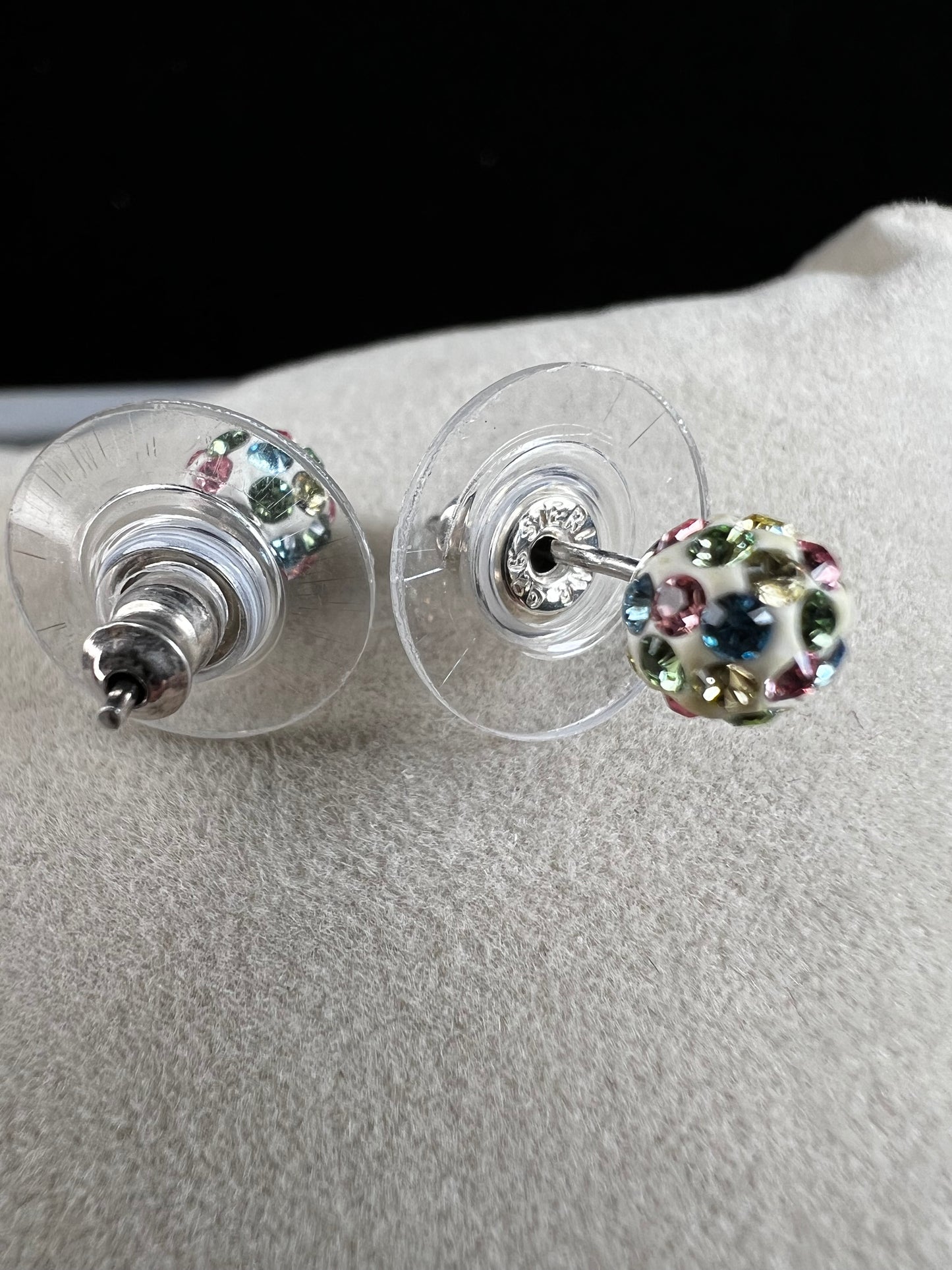 Crafted from sterling silver, these stud earrings are detailed with white enamel and sprinkled with crystals in a variety of colors that create a vibrant sparkle.