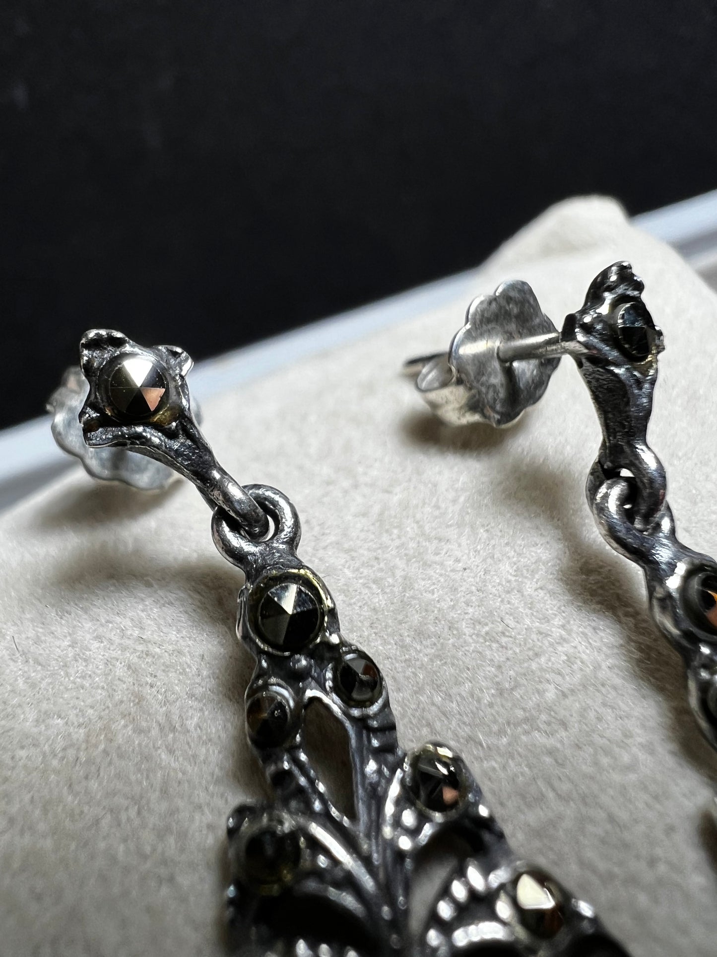 These sterling silver earrings shimmer with marcasite accents and showcase a dangling teardrop of onyx, adding timeless charm and subtle movement.