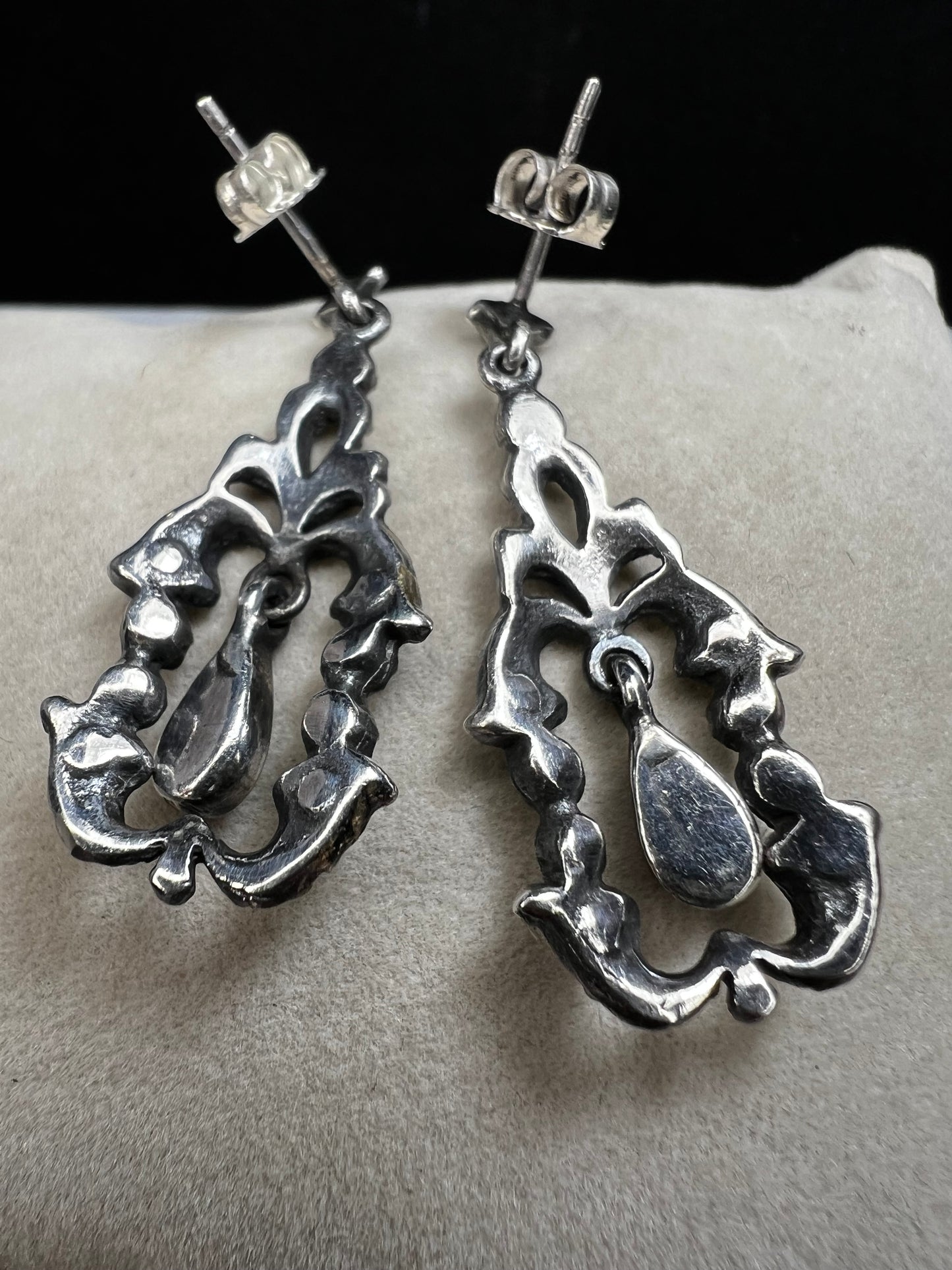 These sterling silver earrings shimmer with marcasite accents and showcase a dangling teardrop of onyx, adding timeless charm and subtle movement.
