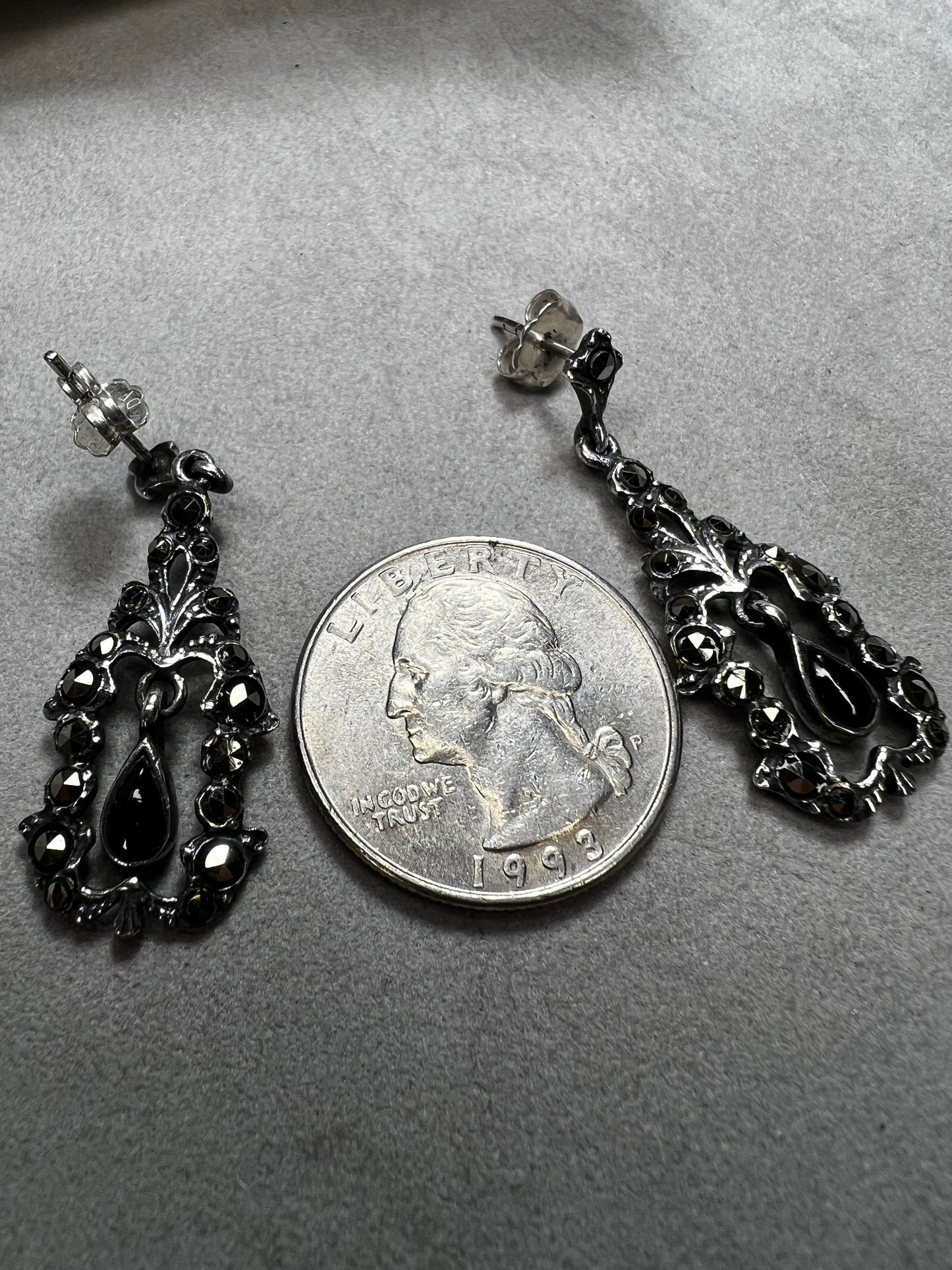 These sterling silver earrings shimmer with marcasite accents and showcase a dangling teardrop of onyx, adding timeless charm and subtle movement.