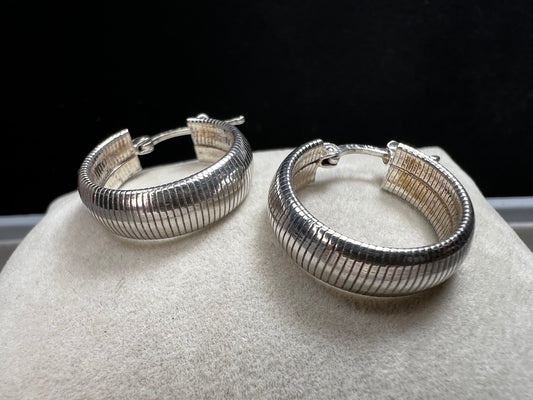 These sterling silver earrings feature a bold, domed design accented by horizontal ridges that catch the light beautifully.