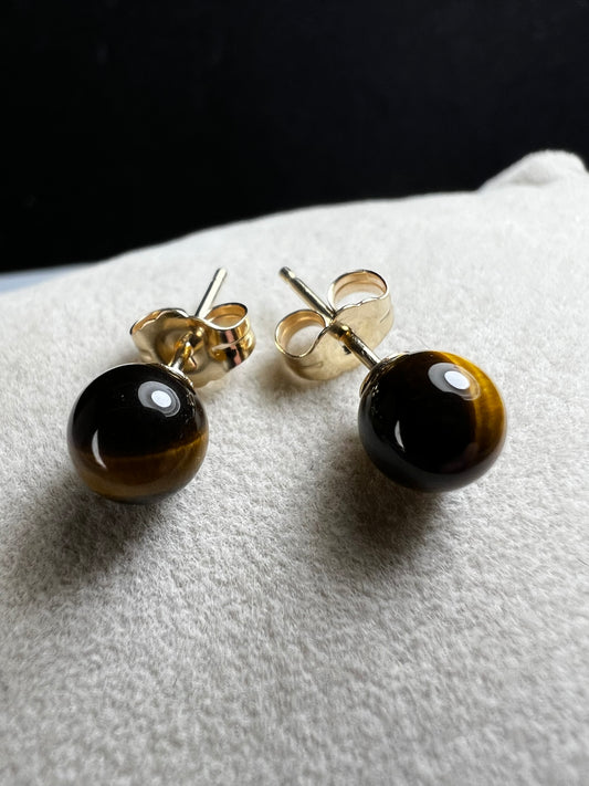 These earrings are crafted with 14 karat gold and feature a beautiful, petite tiger's eye stone.