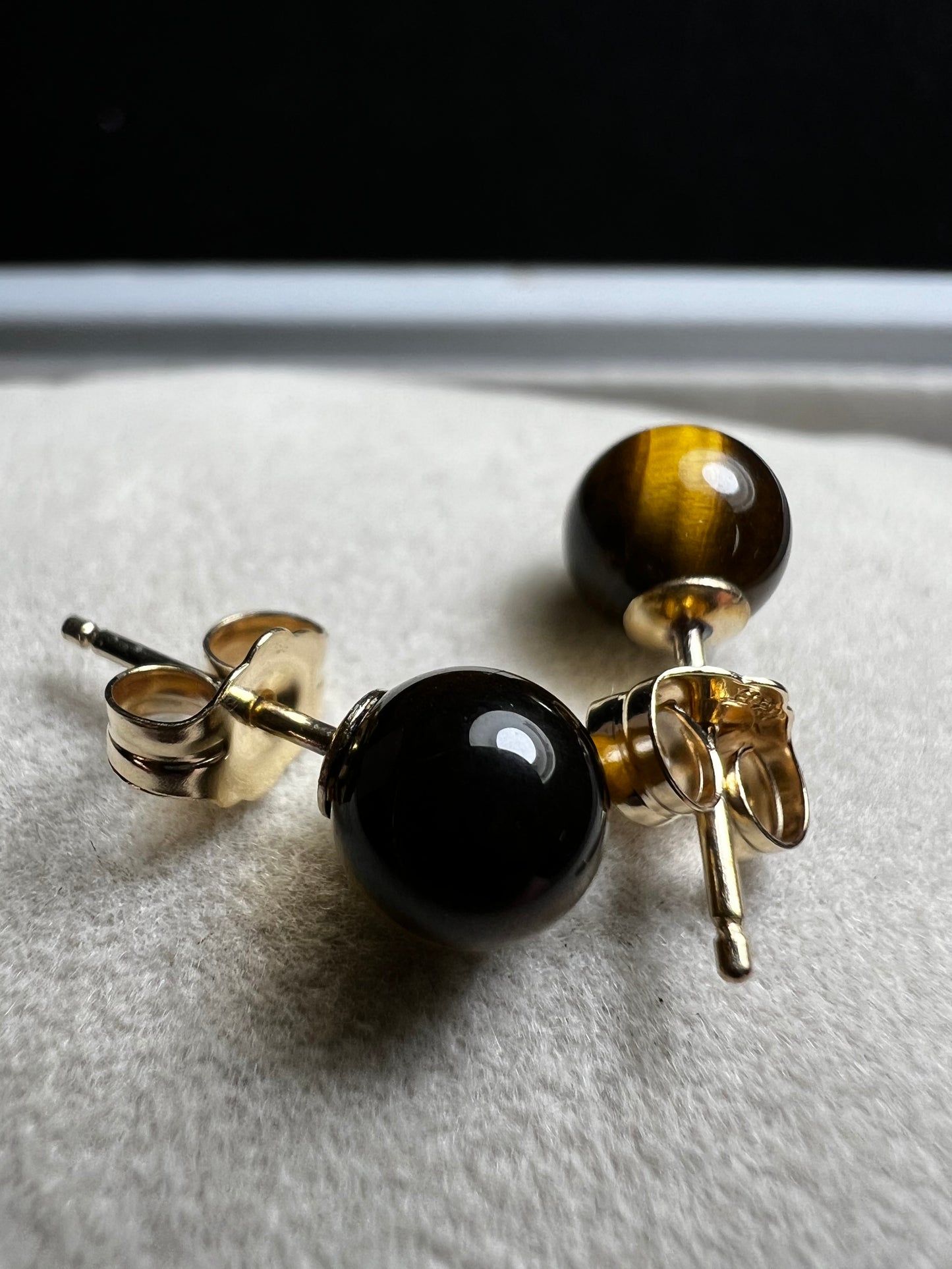 These earrings are crafted with 14 karat gold and feature a beautiful, petite tiger's eye stone.