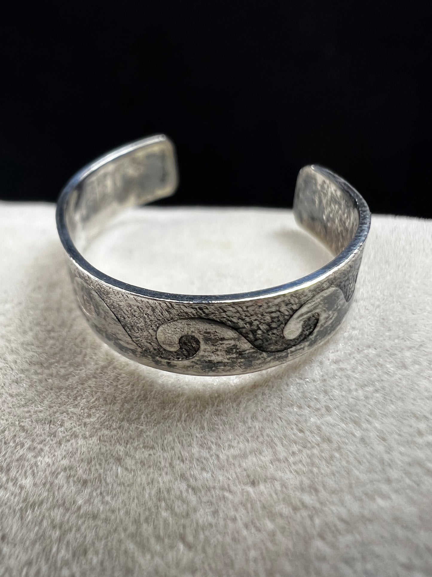 This vintage sterling silver toe ring features an open band with a timeless wave design, ideal for beach enthusiasts. Its detailed craftsmanship captures the effortless spirit of the ocean, making it a refined accessory for seaside or casual wear.