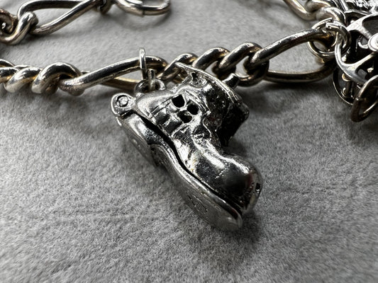 This 1940s sterling silver bracelet features four articulated charms: a Ferris wheel, a gymnastics clown, the old woman in a shoe, and a lighter. Each charm is finely crafted, showcasing detailed workmanship characteristic of the era.