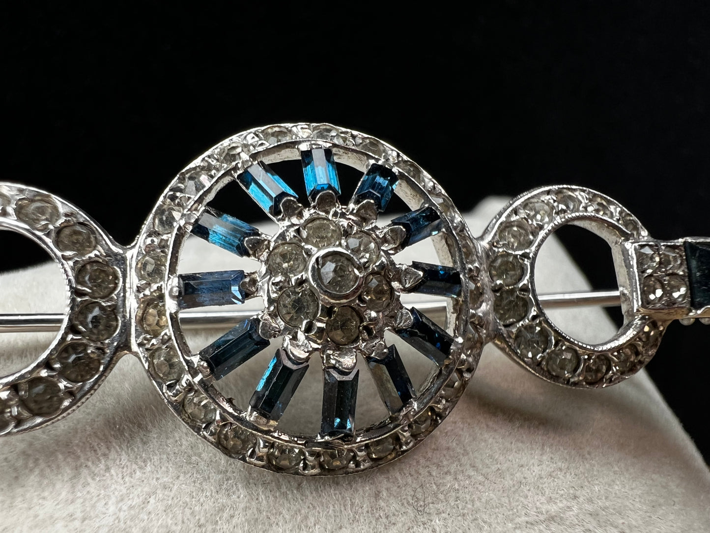 This exquisite sterling silver brooch showcases a refined arrangement of blue and white rhinestones, embodying the elegance of Hollywood Regency design. Signed Otis.