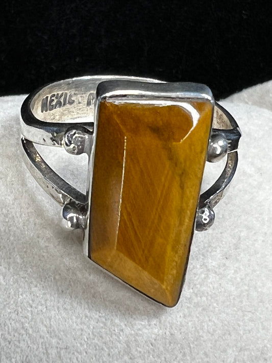 This vintage sterling silver ring features a meticulously cut tiger's eye stone, prized for its warm, reflective bands. The ring is signed Mexico, along with other maker marks.