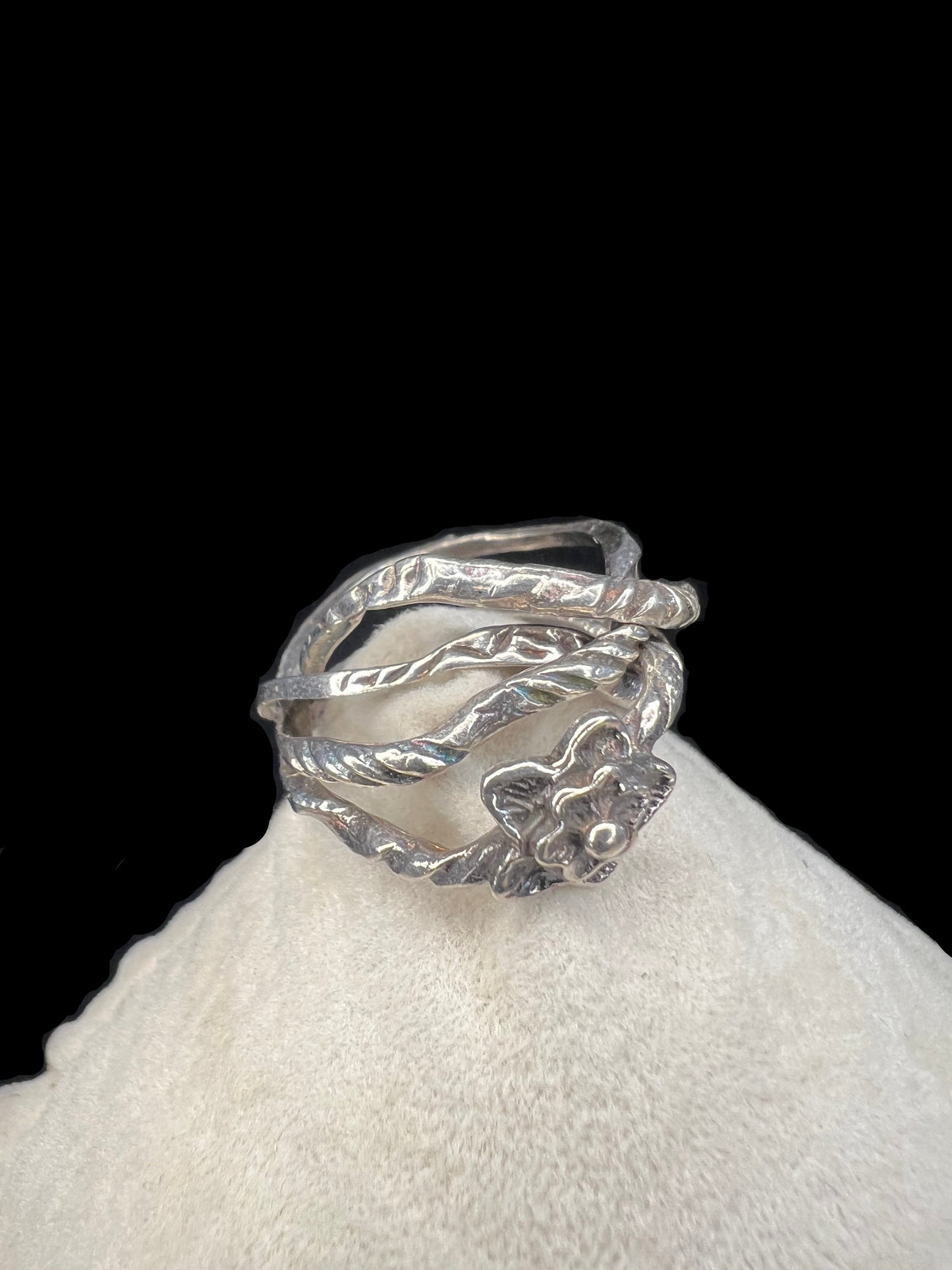 This sterling silver flower ring features four interconnected bands, creating a distinctive and elegant twist on a classic design.
